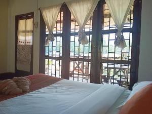 a bedroom with a bed and a large window at VangVieng Ruby'Homestay in Vang Vieng