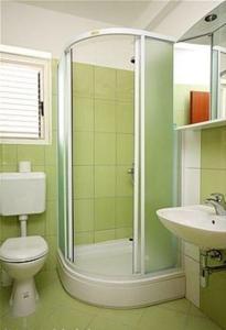 La salle de bains est pourvue d'une douche, de toilettes et d'un lavabo. dans l'établissement Kleines Apartment für zwei Erwachsene und drei Kinder, à Murter