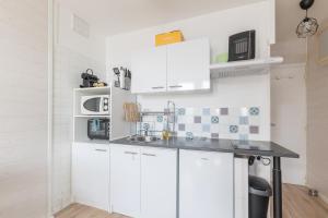 une cuisine blanche avec un évier et un micro-ondes dans l'établissement Studio Alaskan - Studio lumineux vue montagne, à Orcières 3 autres photos