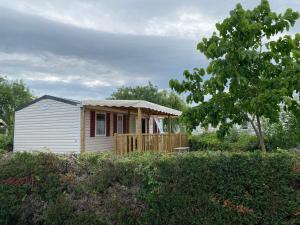 een klein wit huis met een veranda en een boom bij Mobil home 8 personnes in Lattes
