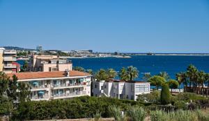 a view of a building with the ocean in the background at MOTEL ASCOT - Hotel & Appartements in Cagnes-sur-Mer