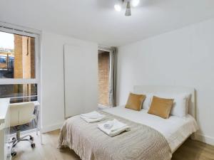 倫敦的住宿－Pass the Keys Stylish 4-Bed3-Bath in Shoreditch，一间卧室配有一张床、一张书桌和一个窗户。