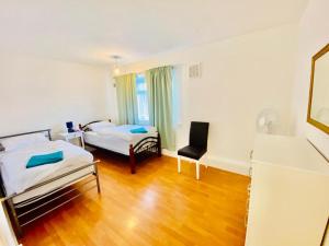 a room with two beds and a chair in it at Wonderful Two Bedroom Apartment in London in The Hyde