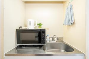 a microwave sitting on top of a kitchen sink at 新宿歌舞伎町東新宿站3分钟，徒步伊势丹4分钟免费Wi-Fi！ in Tokyo