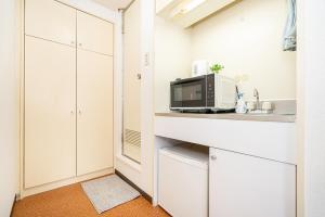 a kitchen with white cabinets and a microwave at 新宿歌舞伎町東新宿站3分钟，徒步伊势丹4分钟免费Wi-Fi！ in Tokyo