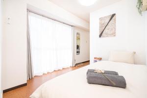 a bedroom with a white bed and a large window at 新宿歌舞伎町東新宿站3分钟，徒步伊势丹4分钟免费Wi-Fi！ in Tokyo