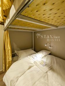 Una cama en una habitación con un cartel que dice "Quédate en un albergue moderno" en STAY Hostel & Motorbike Rental - Thakhek en Thakhek