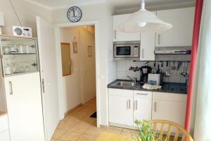 een keuken met witte kasten en een klok aan de muur bij Seepark Sellin FeWo AG Whg 631 in Ostseebad Sellin