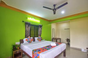 ein grünes Schlafzimmer mit einem Bett und einem Deckenventilator in der Unterkunft The Baga beach 24in in Calangute
