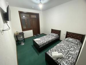 2 camas en una habitación con alfombra verde en Family Hotel, en Samarkand