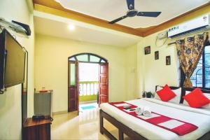 Schlafzimmer mit einem Bett mit roten Kissen und einem TV in der Unterkunft The Baga beach 24in in Calangute