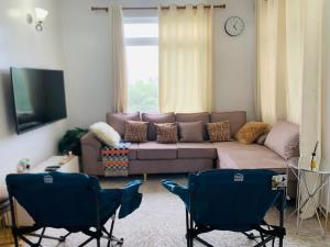 een woonkamer met een bank en 2 stoelen bij A calm stay with free WiFi in Dar es Salaam