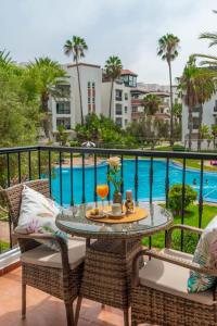 een tafel en stoelen op een balkon met een zwembad bij Luxury Marina Appartement Agadir in Agadir