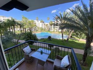 balcón con mesa, sillas y piscina en Luxury Marina Appartement Agadir, en Agadir