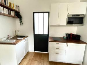 a kitchen with white cabinets and a black door at Casa Londono - Studio #1 - Fonctionnel & cosy in Marly-le-Roi +6 photos