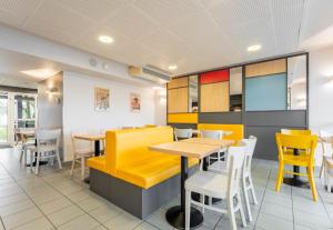 een eetkamer met gele tafels en stoelen bij B&B HOTEL CALAIS Coquelles Tunnel sous La Manche in Coquelles