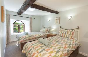 two beds in a room with a window at Barn Owl Cottage Wheddon Cross in Wheddon Cross