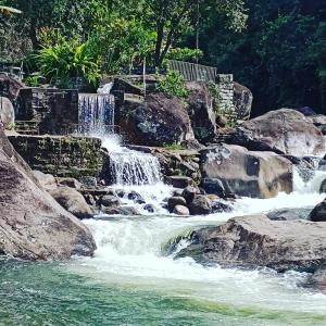 a waterfall in a river with rocks and trees at Conora hotel in Itatiaia