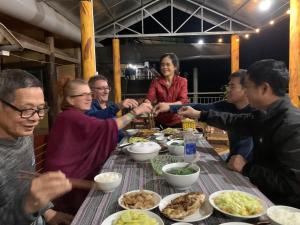a group of people sitting around a table eating food at Dat Diem homestay-wooden floor house in Bak Kan