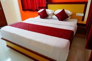 um quarto com uma cama grande e almofadas vermelhas e brancas em Angel Holidays em Munnar