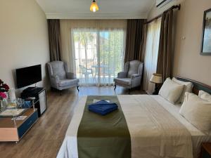 1 dormitorio con 1 cama grande con 2 sillas y TV en High Life en Kyrenia