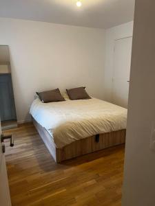 um quarto com uma cama num quarto com pisos em madeira em Moderne Cosy Appartement em Clichy