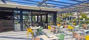 an outdoor restaurant with tables and chairs and windows at AQUA Hotel Onabrava & Spa 4*Sup in Santa Susanna