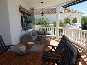 een veranda met een bank en een tafel en stoelen bij Villa Las Campanas in Periana