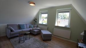 a living room with a couch and a table and two windows at Haus Kiehlwasser Whg 03 OG in Boldixum