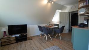 un soggiorno con TV e tavolo con sedie di Haus Kiehlwasser Whg 03 OG a Boldixum