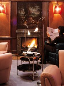 a woman sitting in a living room with a fireplace at Parkhotel Laurin in Bolzano
