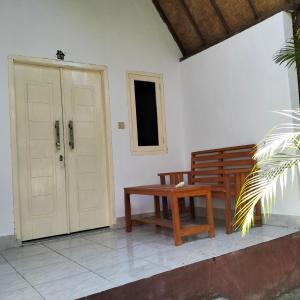 eine Veranda mit einer Bank, einer Tür und einem Tisch in der Unterkunft Putri Nyale Bungalow in Kuta Lombok