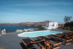 a swimming pool with lounge chairs and a view of the water at The Zen Villa in Akrotiri