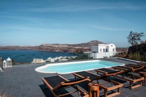 - une piscine avec des chaises longues et une vue sur l'eau dans l'établissement The Zen Villa, à Akrotiri