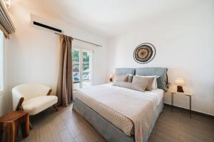 a bedroom with a bed and a chair and a window at The Zen Villa in Akrotiri
