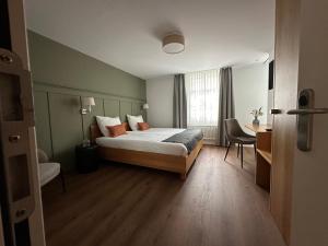 a bedroom with a bed and a desk and a window at Peterhof Sarnen in Sarnen