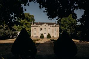 una grande casa bianca con alberi di fronte di Le Petit Serrant - maison d'hôtes d'exception a Bouchemaine