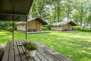 a deck with two huts and an umbrella at Safaritent of Chalet in Neede