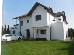 a white house with a car parked in front of it at Villa AnnaLia - Rooms to Rent in Bacău