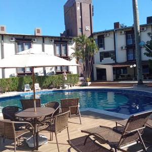 a table with an umbrella next to a swimming pool at Hotel Damen in Foz do Iguaçu