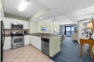 Ocean View Blues- Caribbean Resort 7th fl في ميرتل بيتش: مطبخ مع أجهزة بيضاء وغرفة طعام