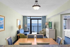 Ocean View Blues- Caribbean Resort 7th fl في ميرتل بيتش: غرفة معيشة مع طاولة وغرفة مطلة