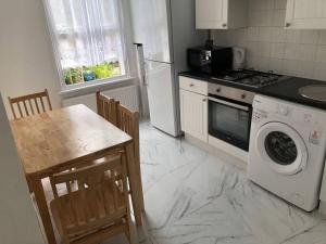 een keuken met een tafel en een wasmachine bij East London 2 bedroom flat in Londen
