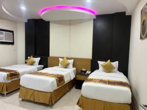 two beds in a hotel room with a pink light at عنوان الرفاهية للشقق المخدومة Eunwan AlRafahia Serviced Apartment in Sharurah