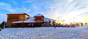 a ski lodge in the snow with people standing outside at The Mountains Hotel in Sierra Nevada