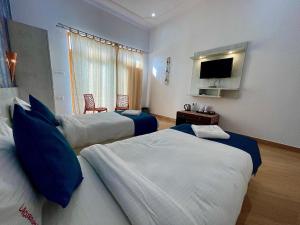 a hotel room with two beds and a flat screen tv at La Curcuma Luxury Homestay in Khajurāho +20 photos