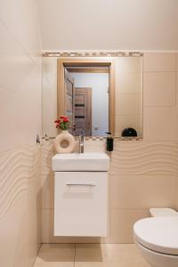 a bathroom with a white sink and a mirror at Apartament Skibówki by LoftAffair in Zakopane