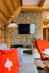 a living room with a stone wall with a flat screen tv at Apartament Skibówki by LoftAffair in Zakopane