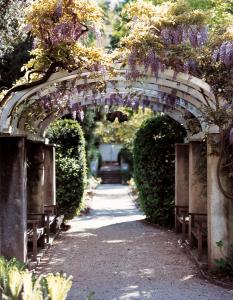 an archway with wisterias and benches in a garden at Parkhotel Laurin in Bolzano