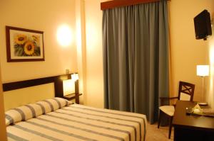 パルマ・デル・リオにあるHotel Castilloのベッド、デスク、窓が備わるホテルルームです。